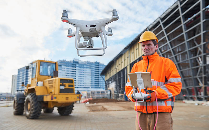 Construction worker piloting drone at building site. video surveillance or industrial inspection